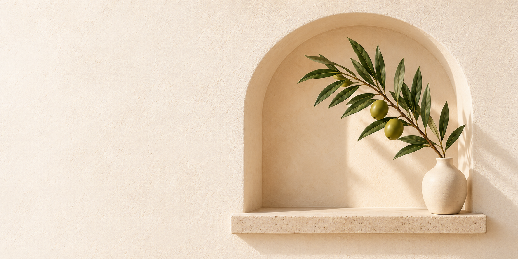 Olive branch in a ceramic vase within a sunlit plaster arch